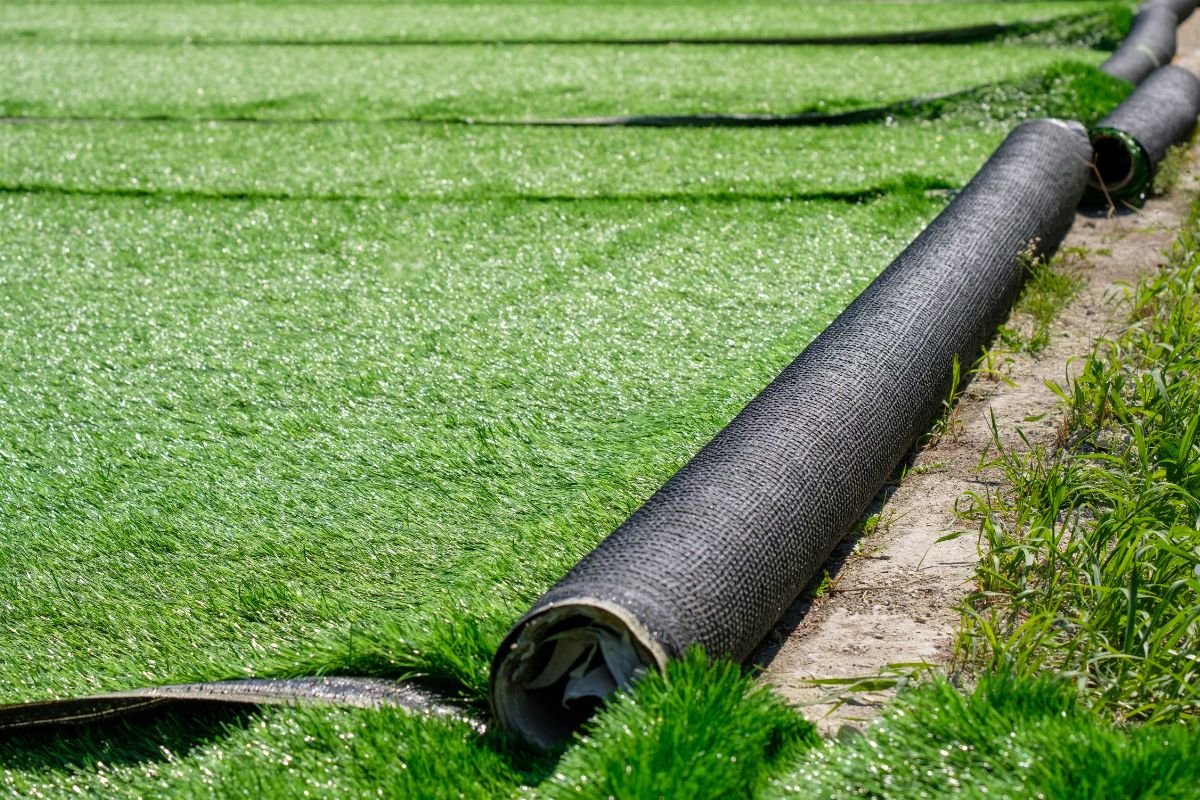 A long black pipe resting on green grass, symbolizing a lawn care service in action.